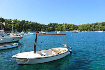 Fototapeta na wymiar View of boat in port in small coast town with clear water and green Mediterranean forest