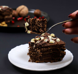 A piece of chocolate dessert cake on a fork on the background of a female hand. Shallow depth of field