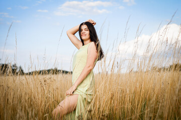 beautiful girl in a dress, standing in the field, against the background of the blue sky	