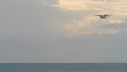 Turboprop aircraft approaching to land over the sea, long shot side view