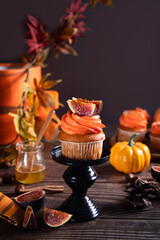 Delicious homemade autumn season spicy pumpkin cupcakes with whipped orange cream with fruit figs.