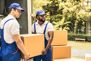 House moving staff is lifting box full of stuff ready for leading into their van in front of customer house.