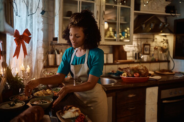 Mid adult black woman preparing food for Christmas lunch in kitchen.