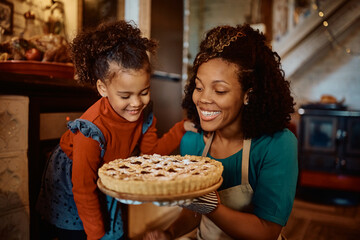 Happy black mother and daughter with sweet pie they baked for Thanksgiving meal. - Powered by Adobe