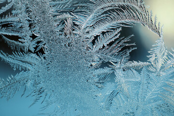 Abstract Christmas background. Ice crystals on frozen window glass. Frost drawing. Dark blue tinted wallpaper similar to moonlit winter night. Rime frosting pattern. Cold and crystal. Macro