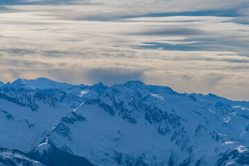 View of the snow-capped mountains in the Schmitten ski area in Zell am See. In the background is a beautiful sky with clouds.