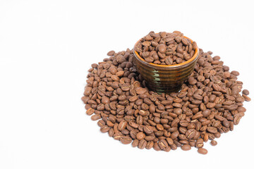 A small saucer with coffee beans stands on a pile of coffee on a white background.