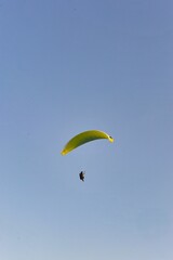 Vertical shot of a paraglider with a clear sky background