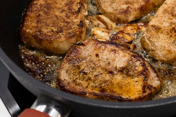 Tender pork steaks with garlic, fried in a pan. Cooking food at home. Close-up