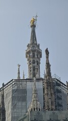 Fototapeta na wymiar Milan Italy- October 17, 2022: Milan cathedral Duomo di Milano with gothic spires and white marble statues. Top tourist attraction on piazza in Milan, wide angle view of old gothic architecture.