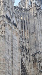 Obraz premium Milan Italy- October 17, 2022: Milan cathedral Duomo di Milano with gothic spires and white marble statues. Top tourist attraction on piazza in Milan, wide angle view of old gothic architecture.