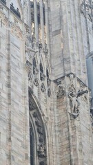 Naklejka premium Milan Italy- October 17, 2022: Milan cathedral Duomo di Milano with gothic spires and white marble statues. Top tourist attraction on piazza in Milan, wide angle view of old gothic architecture.