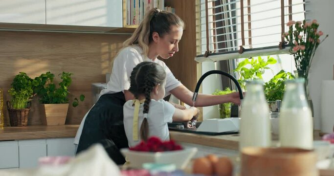 Selective focus on prepared kitchen ingredients for pizza delighted mother and adorable preschooler little daughter washing hands before starting cooking baking breakfast surprise for father.