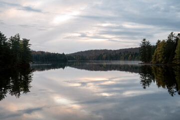 Clouds reflecting on a calm, tree lined lake. Maple Leaf Lake, Algonquin Provincial Park, Ontario, Canada.