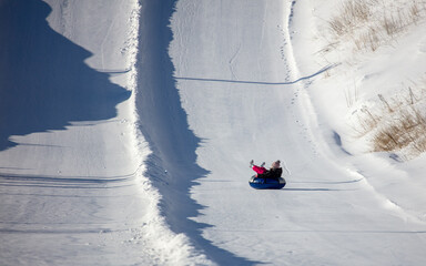 A child rolls down a snow tubing from a mountain.