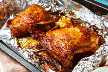 Chicken pieces with a crispy crust in sauce baked in foil on a baking sheet.