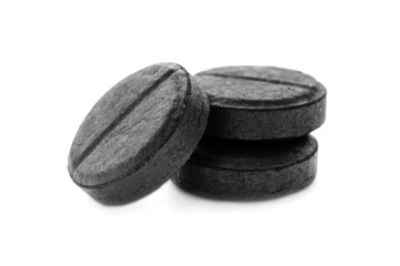 Activated charcoal tablets isolated on white background, close-up. Black tablets of activated charcoal on a white background, macro. Activated charcoal tablets isolated on white background, macro.