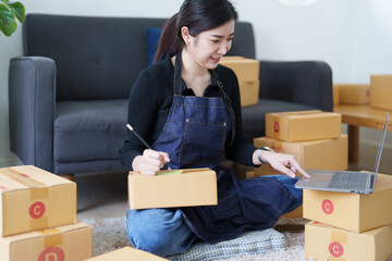 Startup small business entrepreneur of freelance Asian woman smiling and using laptop computer with Cheerful success of item online marketing packaging box and delivery SME idea concept