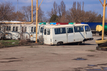 Fototapeta na wymiar The old written-off minibusses are in the auto transport company. Decommissioned vans are rusting in the open air, and a junkyard of vehicles