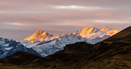 Sunrise with colourful snow peaks early morning in the Swiss alps, layers of mountains on a nice autumn day