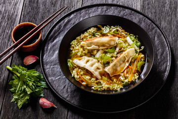 Asian Gyoza Soup in black bowl, top view