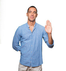 Fototapeta premium Happy young man making a gesture of stop with his palm