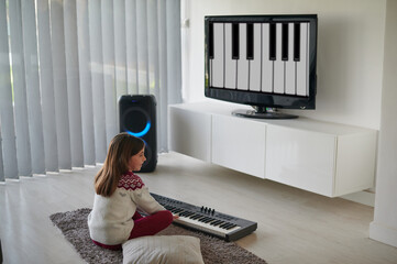 Adorable child learning piano lessons at home