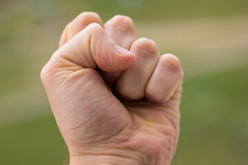 Hand clenching a fist on a green background close-up