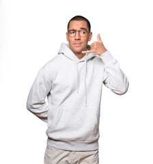 Hesitant young man making a gesture of calling with the hand