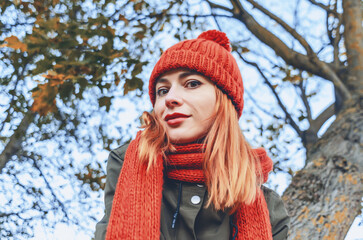 Autumn fashion portrait of a stylish woman in a bright orange knitted hat and scarf. Playful look.