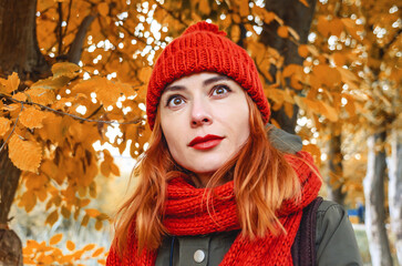 Dreamy woman with red hair and black eyes enjoying nature in autumn forest. Yellow leaves.