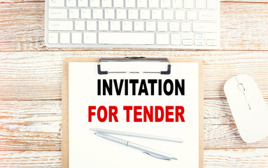 INVITATION FOR TENDER text on a clipboard with keyboard on wooden background