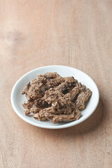 sun dried ginger on a white plate, flavoring and herbal ingredient with strong health benefits on a wooden table top, taken with copy space