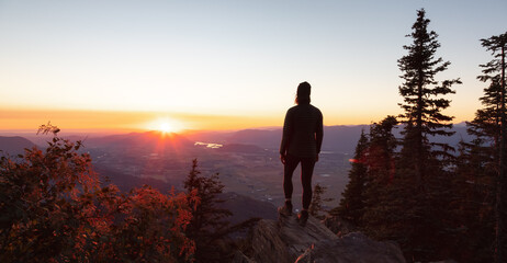 Adventurous Woman Hiking in Canadian Landscape with Fall Colors during sunny sunset. Elk Mountain,...