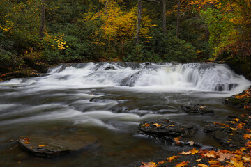Motion-blurred water of Dingmans Creek surrounded by fall color