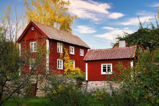 Typical red wooden house and cottage with a beautiful garden in Scandinavia.