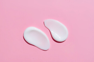 Smears of cosmetic cream or lotion on pink background. smear smudge stroke on color background. Creamy beauty product closeup