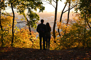 young couple at sunset on an autumn day with the cityscape at the background