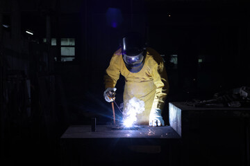 Industrial technician with Welding PPE weld metal structure in factory, metal welding in factory