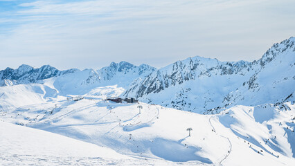 Ski lift cross centre on a snowy peak in beautiful winter scenery with mountain range in a...