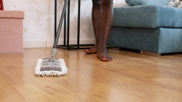 Man cleaning the floor of his house with a mop.