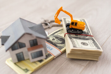 Small house and excavator, dollar bills