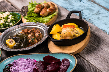 Eid Mubarak Traditional Ramadan Iftar dinner. Assorted tasty food in authentic rustic dishes on wooden blue background. Turkish Bosnian food meat kebab, pita, Sarma, klepe, sogan dolma.