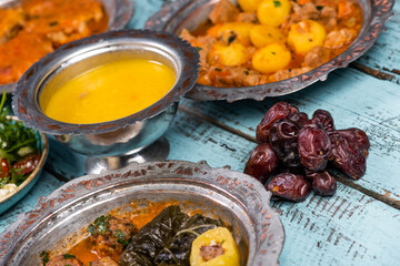 Eid Mubarak Traditional Ramadan Iftar dinner. Assorted tasty food in authentic rustic dishes on wooden blue background. Turkish Bosnian food meat kebab, pita, Sarma, klepe, sogan dolma.