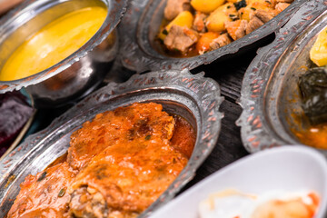 Eid Mubarak Traditional Ramadan Iftar dinner. Assorted tasty food in authentic rustic dishes on wooden blue background. Turkish Bosnian food meat kebab, pita, Sarma, klepe, sogan dolma.