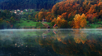 Fototapeta na wymiar Fall colours and cottage reflected in the still waters of Lake.Autumn nature. Vivid morning in colorful park