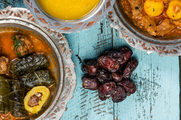 Eid Mubarak Traditional Ramadan Iftar dinner. Assorted tasty food in authentic rustic dishes on wooden blue background. Turkish Bosnian food meat kebab, pita, Sarma, klepe, sogan dolma.