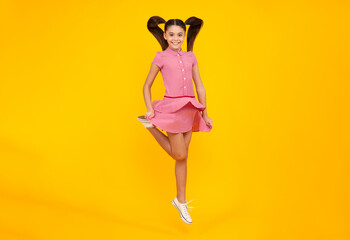 Excited teenager. Full length funny teenager kid jump enjoy rejoice win isolated on yellow...