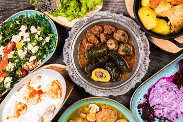 Eid Mubarak Traditional Ramadan Iftar dinner. Assorted tasty food in authentic rustic dishes on wooden blue background. Turkish Bosnian food meat kebab, pita, Sarma, klepe, sogan dolma.