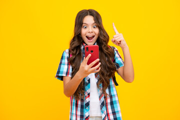 Mobile online shopping. Cute teen child girl paying with phone, texting and chatting on smartphone. Amazed teen girl. Excited expression, cheerful and glad.